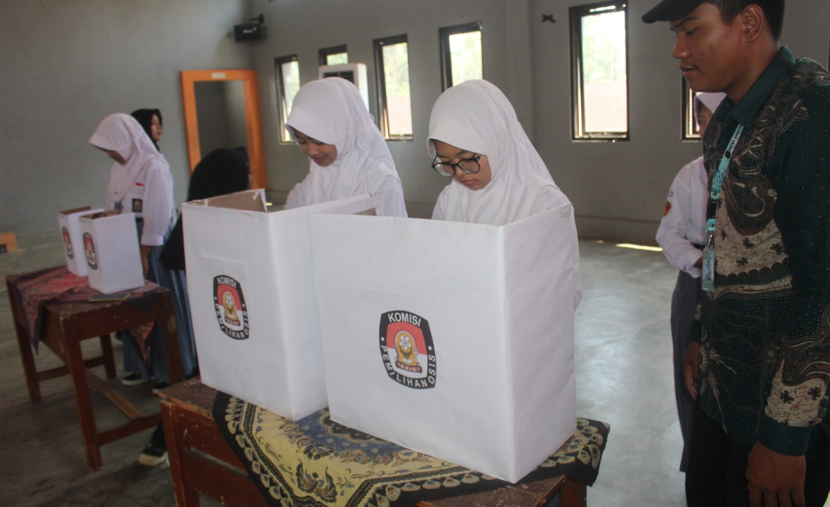 Seorang panitia Pilketos SMKN Bantarkalong sedang memperhatikan sejumlah siswa perempuan menggunakan hak suaranya di biliki suara (Dok: OSIS SMKN Bantarkalong)

